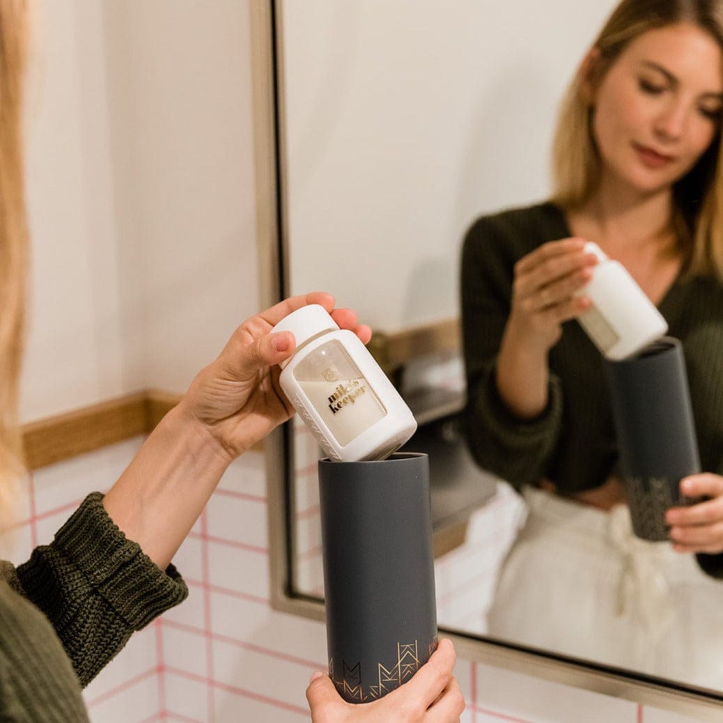 Mother putting pumped breast milk into Mila's Keeper Insulated Cooler in public bathroom.